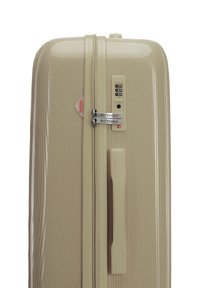 Maleta rígida en beige claro, con un patrón texturizado, cerradura combinada, doble cremallera y un asa lateral.