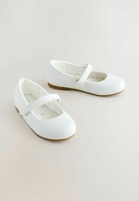 White leather ballet flats with a rounded toe and a strap across the top. Flat brown rubber soles. Smooth texture with minimal detailing.