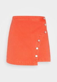 Jupe en denim orange avec un design enveloppant, ornée de boutons-pression en acier sur le côté gauche et d'un ourlet droit. Texture douce.