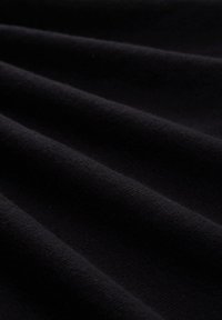 Schwarzer Stoff mit glatter Textur, der weiche Falten und subtile Fasern zeigt, die in unterschiedlichem Licht und Schatten präsentiert werden.