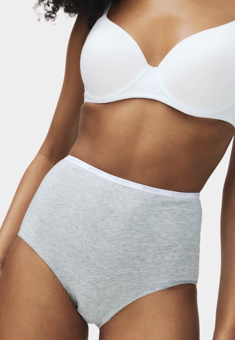 Femme portant un soutien-gorge blanc et une culotte taille haute en coton gris clair avec l'inscription "BODY" sur la ceinture.