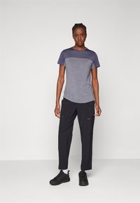 Koszulka z krótkim rękawem, okrągłym dekoltem w ciemnoszarym kolorze z jaśniejszym szarym panelą u góry. Połączona z czarnymi spodniami typu cargo z zamykanymi kieszeniami.