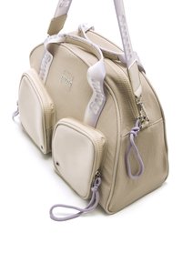 Beige synthetische Tasche mit zwei kleinen Seitentaschen, verstellbarem lavendelfarbenem Gurt, glatter Textur und minimalistischem Design mit einem Logo.