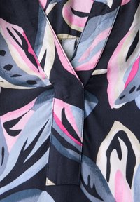 Tessuto a fantasia floreale con grandi foglie in tonalità di rosa, blu e crema, su uno sfondo scuro con design a V.