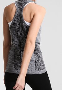 Canotta grigia con motivo animalier, stile racerback, caratterizzata da un mix di tessuti testurizzati e una silhouette aderente. Accenti neri ai lati.