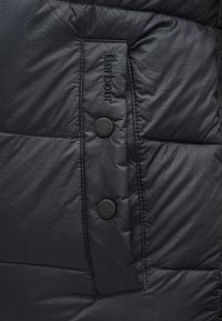 Μπλε ναυτικό μπουφάν με επένδυση, χαρακτηριστική απαλής υφής, στρογγυλά κουμπιά και ραμμένο έμβλημα με το όνομα της μάρκας "Barbour".