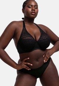 Juoda bikini rinkinys, kuriame yra halter tipo liemenėlė su permatomu džiugu audiniu ir suderinta bikini apatinė dalis. Lygus audinys su geometriniais akcentais.