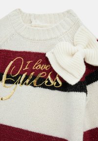 Maglione a righe rosse e nere con base crema, caratterizzato da un ampio fiocco crema e testo dorato in paillettes "I love Guess" sul davanti.