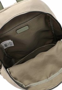 Khakin värinen reppu, jossa sileä pinta, suuri pääosasto, vetoketjullinen tasku ja vuoriin ommeltu nimiketiketti.