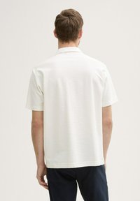 Witte shirt met korte mouwen van een lichte, gestructureerde stof. Beschikt over een klassieke kraag en een rechte zoom, met een achterkant die minimaal gedetailleerd is.