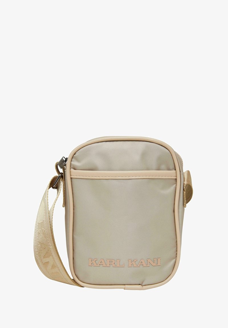 Beige nylon crossbody bag with a rectangular shape, zip closure, front pocket, and woven strap. Brand name "KARL KANI" in embossed lettering.