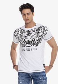 Weißes Baumwoll-T-Shirt mit einem großen schwarzen Tiger-Graphic mit Flügeln, rundem Halsausschnitt und kurzen Ärmeln. Darunter sind abgewetzte Jeans sichtbar.