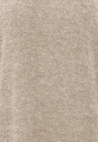 Tissu beige en laine douce avec une texture duveteuse et des fibres fines visibles sur toute la surface.