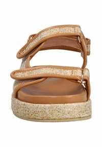 Tan platform sandaal met geweven stroaccenten, meerdere verstelbare banden en een gladde afgeronde neus. Voorzien van metalen hardware en een gestructureerde zool.