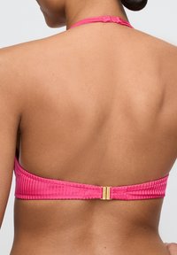Różowy, żeberkowany biustonosz bikini z zapięciem na plecach. Tekstura materiału jest gładka. Sznurek na szyję przechodzi w szeroki, płaski pas na plecach.