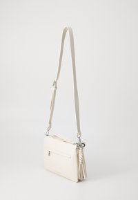 Borsa a tracolla bianca in pelle con una sottile tracolla regolabile, chiusura con zip e una tasca frontale. Presenta dettagli in argento e una superficie liscia.