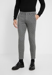 Grå mönstrade byxor med slim fit-design, som har ett texturerat tyg och sidofickor. Kombinerade med svarta skor och en långärmad topp.