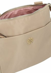 Beige Nylon Tasche mit glatter Textur, Reißverschlussverschluss und rosa Innenfutter. Verfügt über ein geprägtes Logo auf der Vorderseite.
