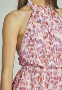 Rosa plissiertes Kleid mit Neckholder, das abstrakte lila und rote Blumenmuster zeigt. Weicher Stoff mit leichter Textur.