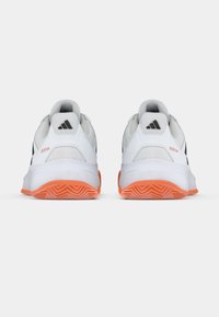 Λευκά αθλητικά παπούτσια με μαύρες λεπτομέρειες, πάνω μέρος από υφή με δίχτυ και πορτοκαλί λαστιχένια σόλα. Διαθέτουν μαξιλαρωμένο γιακά και λεπτομέρεια με λογότυπο.