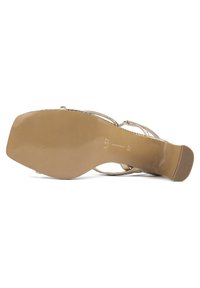 Sandale à bout carré, fines lanières dorées, petit talon bloc, semelle beige lisse de taille 37 vue par le dessous.
