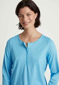 Lichtblauw langemouwen shirt met een ronde hals, knoopsluiting en zachte textuur. Heeft een relaxte pasvorm en soepele stof.