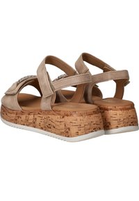 Beige suède sandalen met een kurken platformzool. Voorzien van verstelbare banden en decoratieve accenten op de bovenkant. Textuur van het kurkdetail zichtbaar.