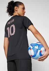 Black sports jersey with pink "MESSI" and "10" on the back. The player holds a multicolored soccer ball with blue, red, and white patterns.