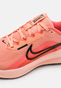 Nike Sneaker mit einem Obermaterial aus Netz in Koralle, schwarzen Akzenten, strukturierten Überzügen und einer gepolsterten Sohle für Unterstützung.