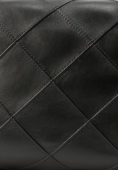 Μαύρη δερμάτινη επιφάνεια με διακοσμητικό μοτίβο ρόμβων που δημιουργείται από ραφές τοποθετημένες σε ίση απόσταση μεταξύ τους.