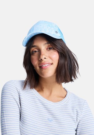 Hellblaues Cap mit strukturiertem Muster, gebogenem Schirm und metallischem Akzent. Kombiniert mit einem gestreiften blau-weißen Langarmshirt.