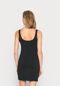 Svart ärmlös klänning med rundad rygg, figurnära design och slätt tyg. Kjolen är över knäna och ger en minimalistisk look.