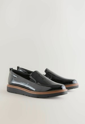 Schwarze Lackleder Slipper mit einer strukturierten Gummisohle und kontrastierenden, tannfarbigen Nähten. Mit elastischen Seitenteilen für ein einfaches An- und Ausziehen.