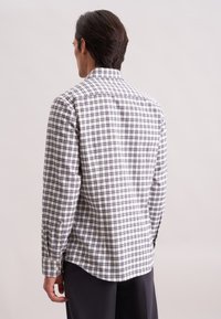 Camicia a maniche lunghe a quadri bianchi e blu navy con colletto, polsini abbottonati e orlo curvo. Il tessuto sembra leggero e texture.
