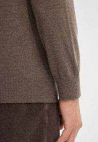 Brązowy sweter dziany z prążkowanymi mankietami i dołem, charakteryzujący się gładką fakturą, dopasowanym krojem i subtelnymi detalami szycia.