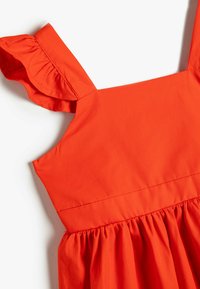 Oranges Baumwollkleid mit weit ausgestellten Trägern, gerafftem Taillenschnitt und glatter Textur, das ein verspieltes und lebendiges Design hervorhebt.