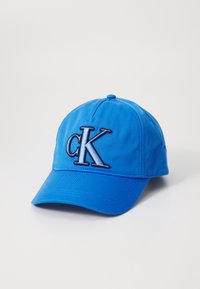 Blauwe baseballpet van stof, met een geborduurd "CK" logo aan de voorkant in zwart en zilver. Gebogen klep en verstelbare achterkant.