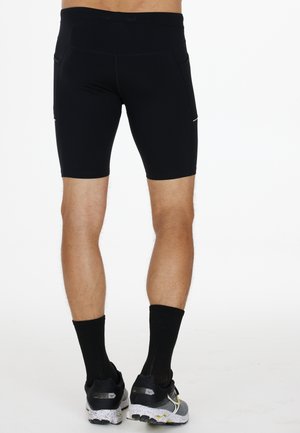 Sorte athletic shorts med en tætsiddende pasform, der har en høj talje, sidelommer og en glat tekstur. Pyntet med reflekterende detaljer.