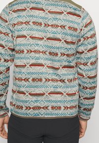 Pull en tricot avec un fond texturé gris présentant des motifs géométriques bleus, rouges et verts. Poignets côtelés ; accents olive sur les épaules.