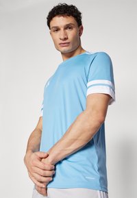 Light blue athletic T-shirt with white accents and stripes on sleeves. Made from breathable material, featuring a crew neckline and slim fit.