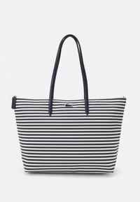 Sac fourre-tout rayé avec des rayures verticales bleu marine et blanches, en tissu lisse, avec deux longues poignées, fermeture éclair, et un petit logo en accent.