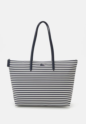 Bolsa de tote riscada com riscas verticais em azul marinho e branco, tecido suave, duas alças longas, fecho de zíper, com um pequeno logotipo em destaque.