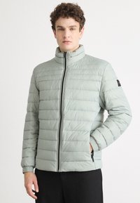 Light green puffer jacket with horizontal quilted design, high collar, front zipper, and elastic cuffs. Features side pockets and black accents.