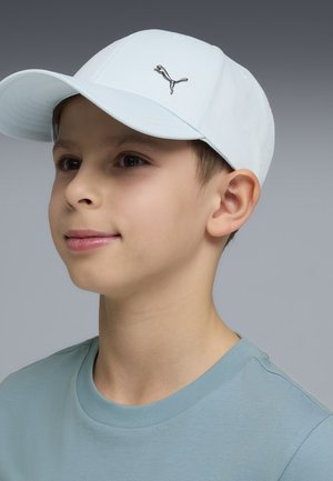 Jasnoniebieska czapka z tkaniny z srebrnym logo z przodu. Osoba ma krótkie brązowe włosy i ubrana jest w niebieską koszulę.