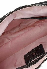 Interno di una borsa nera con zip, foderata in un rosa liscio, dotata di un'etichetta e un bordo testurizzato vicino alla zip. Design semplice con una finitura morbida.