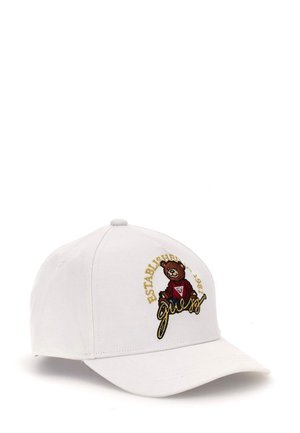 Cappellino da baseball bianco con visiera curva, caratterizzato da un logo di orso ricamato in testo marrone e oro che legge "FONDATO NEL 1981 Guess."