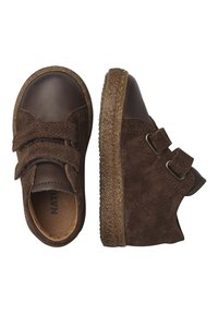 Scarpe in suede marrone con due cinturini in velcro, punta arrotondata e suola in gomma texture. Dettagli in morbida pelle intorno alla parte superiore.