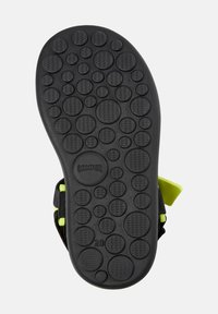 Musta kumipohja, jossa on vaihtelevaa pyöreää tekstuuria, varustettuna kohotetuilla pisteillä pidon parantamiseksi. Mukana "CAMPPER" -brändäys ja kokoaindikaattori, 28.