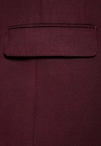 Burgundowa tkanina z teksturowanym wzorem. Posiada poziomą klapkę kieszeni, wykończone krawędzie oraz usztywnioną konstrukcję.