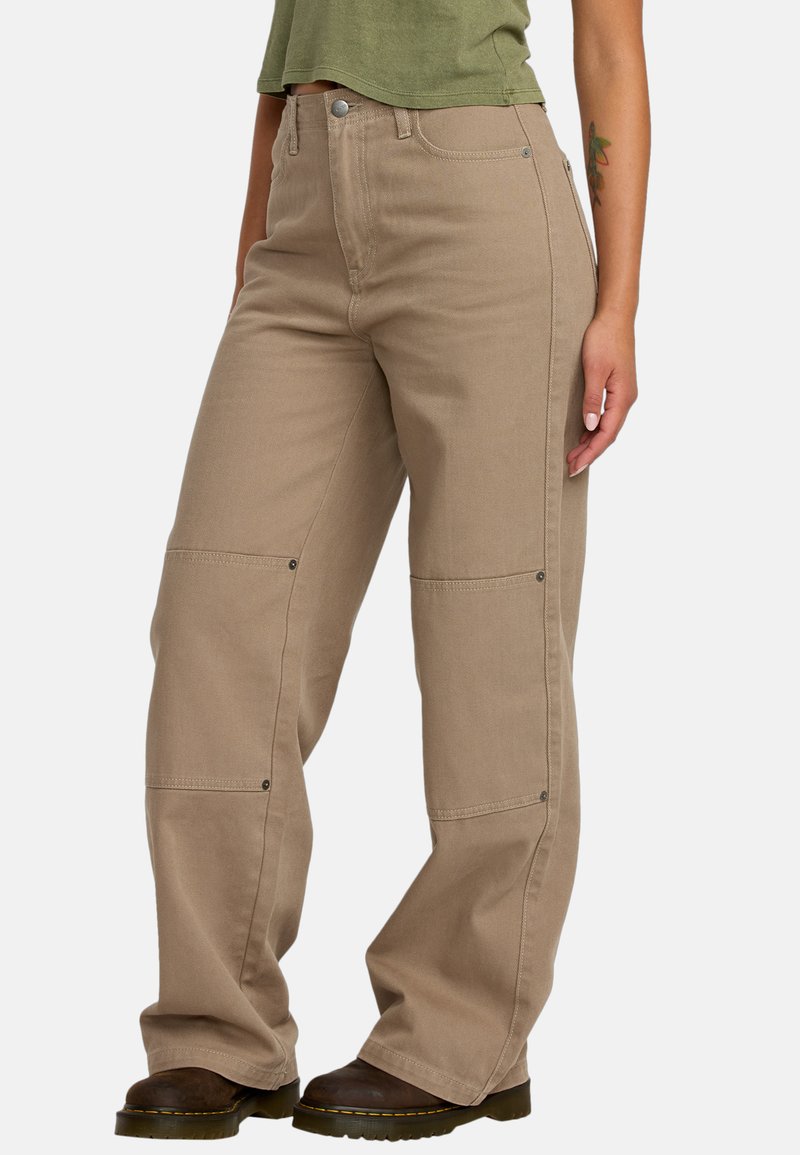 Beige cargo pants made of durable fabric, featuring side pockets, button closures, and a relaxed fit. Paired with dark boots.